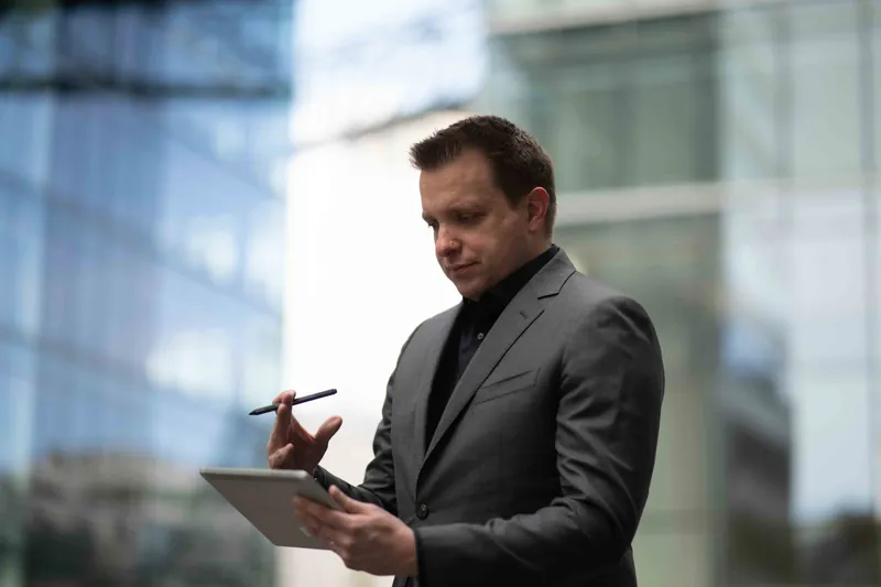Benjamin Aunkofer mit Tablet vor einer Glasfassade