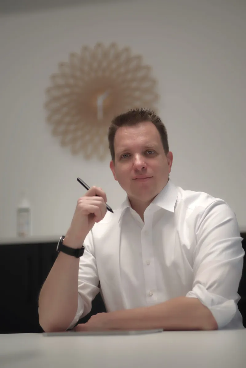 Benjamin Aunkofer am Schreibtisch, freundlich in die Kamera blickend